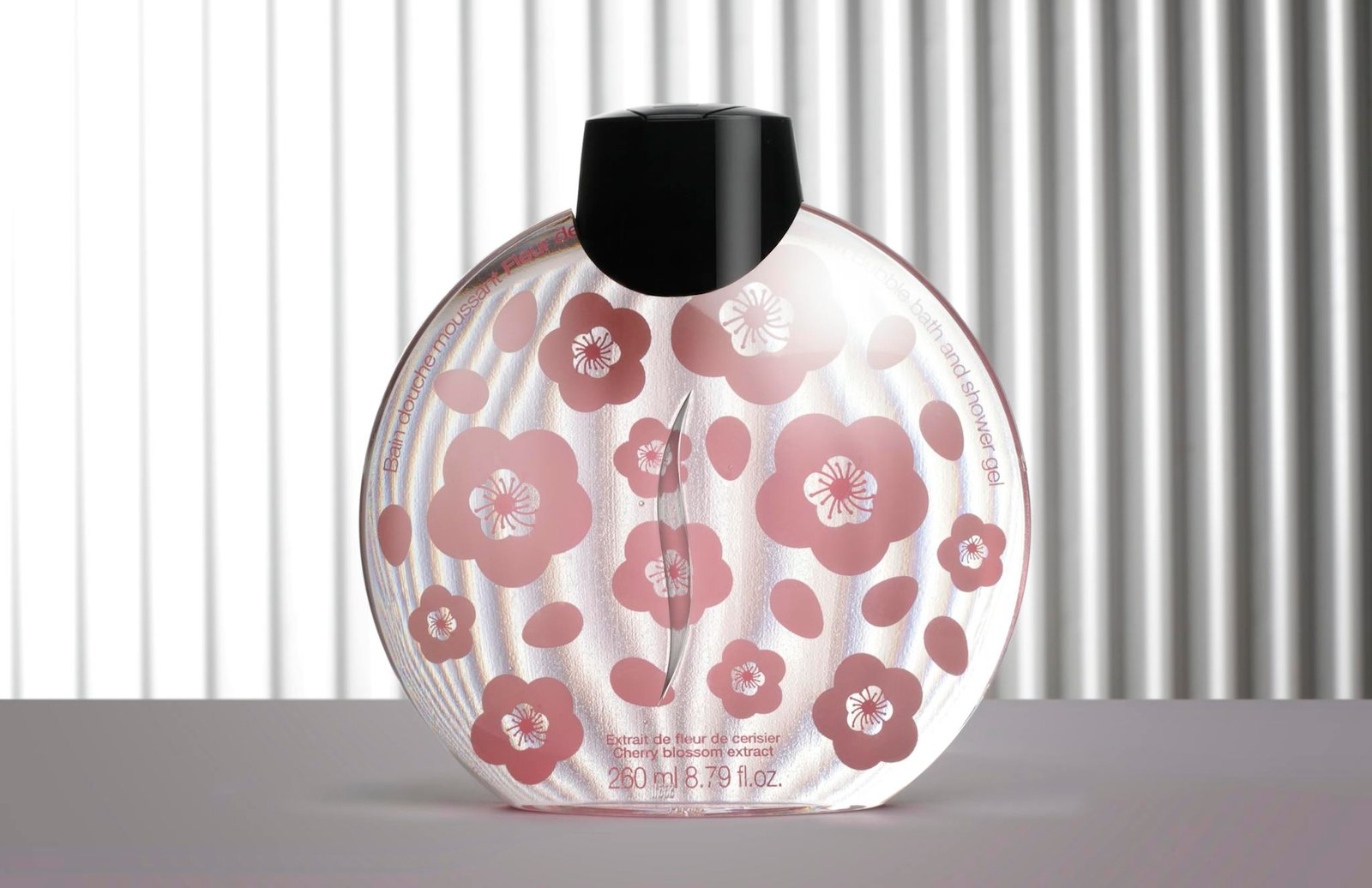 Elegant perfume bottle with cherry blossom design against a striped background.